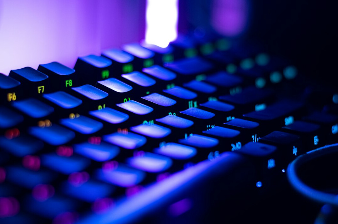 Close-up of hands typing code on a laptop keyboard with a second monitor showing a website