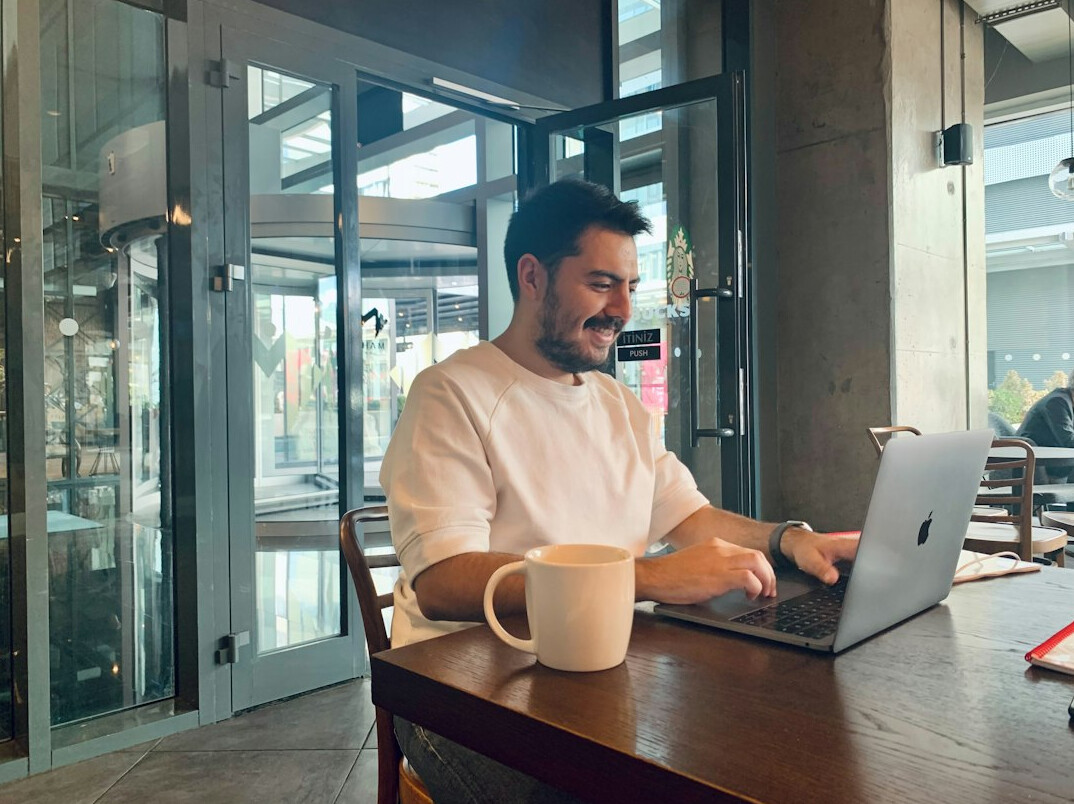 person coding on laptop in cafe