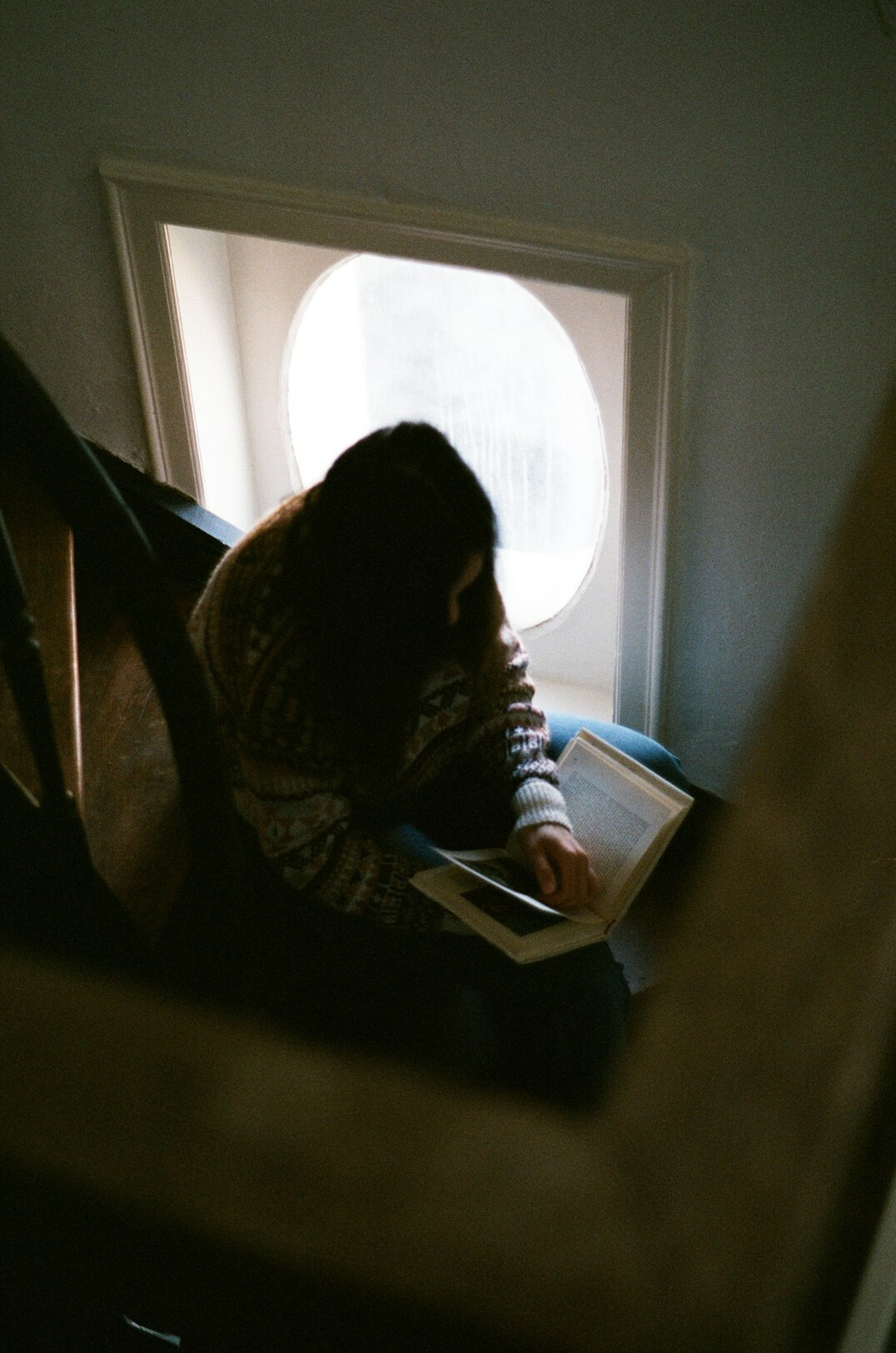 person reading book near window